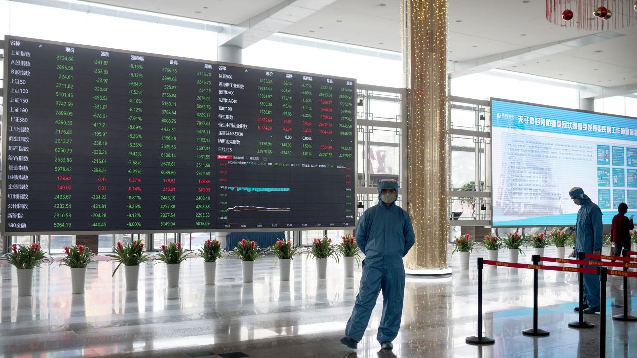 Workers wearing protective suits stand near an electronic display board in the lobby of the Shanghai Stock Exchange building in Shanghai, Monday, Feb. 3, 2020. The Shanghai Composite index tumbled 8.7% Monday then rebounded slightly as Chinese regulators moved to stabilize markets reopening from a prolonged national holiday despite a rising death toll from a new virus that has spread to more than 20 countries. (AP Photo)