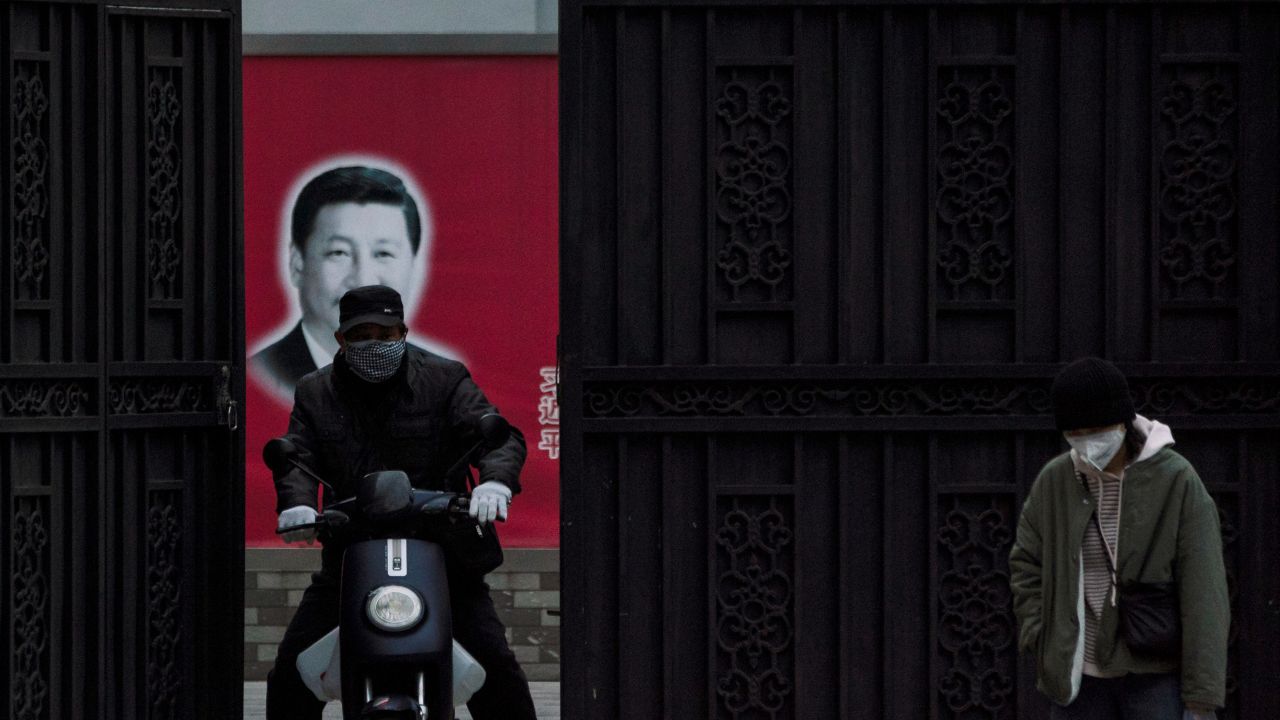 People wearing masks are seen in front of a portrait of Chinese President Xi Jinping on a street as the country is hit by an outbreak of the novel coronavirus, in Shanghai, China, February 10, 2020. REUTERS/Aly Song (China)