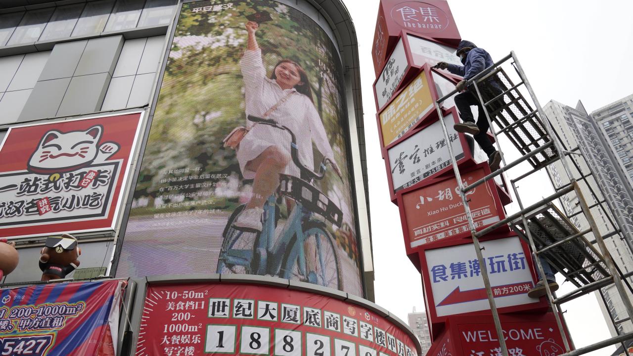 Workers clean up signboards outside a retail center in Wuhan in central China's Hubei province on Saturday, Jan. 16, 2021. China eked out 2.3% economic growth in 2020, likely becoming the only major economy to expand as shops and factories reopened relatively early from a shutdown to fight the coronavirus while the United States, Japan and Europe struggled with disease flare-ups. (AP Photo/Ng Han Guan)